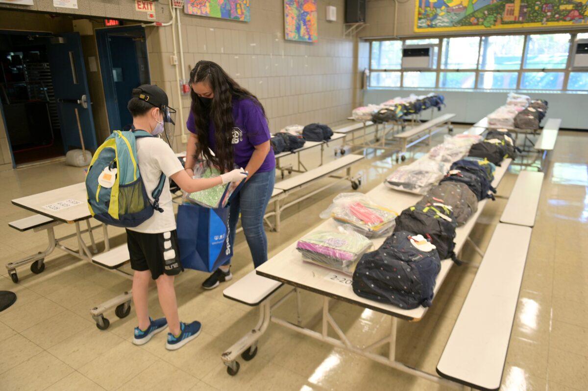 Schoolteacher Aurora Chen hands belongings left behind before schools were shut down to a student who just graduated at Yung Wing School P.S. 124 in New York City, on June 29, 2020. (Michael Loccisano/Getty Images)