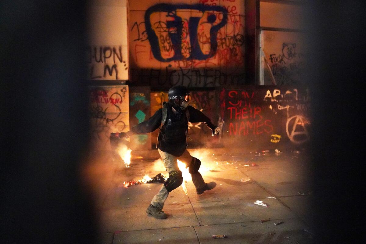 A protester throws a flaming object toward the Mark O. Hatfield U.S. Courthouse after breaking through the perimeter fence, in Portland, Ore., on July 22, 2020. (Nathan Howard/Getty Images)