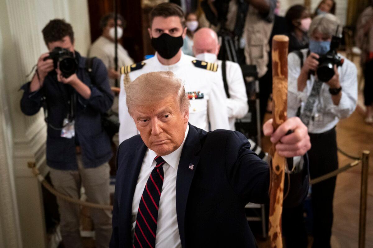 President Donald Trump holds up a walking stick given to him by Sen. Lamar Alexander (R-Tenn.) after he signed the Great American Outdoors Act at the White House in Washington on Aug. 4, 2020. (Drew Angerer/Getty Images)