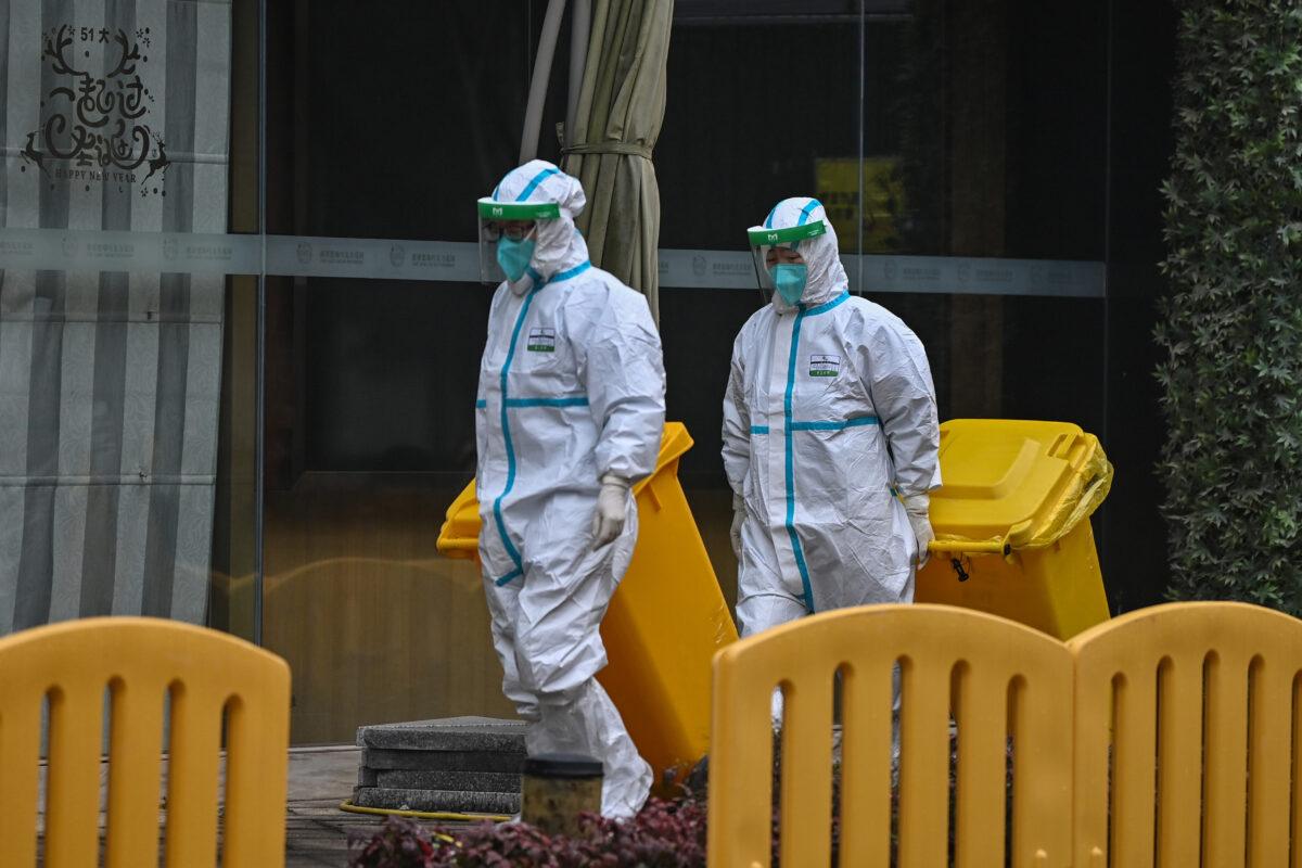 Workers wearing protective gear are seen in the compounds of The Jade Boutique Hotel, where members of the World Health Organization team investigating the origins of the COVID-19 pandemic were due to complete their quarantine in Wuhan, China, on Jan. 28, 2021. (Hector Retamal/AFP via Getty Images)