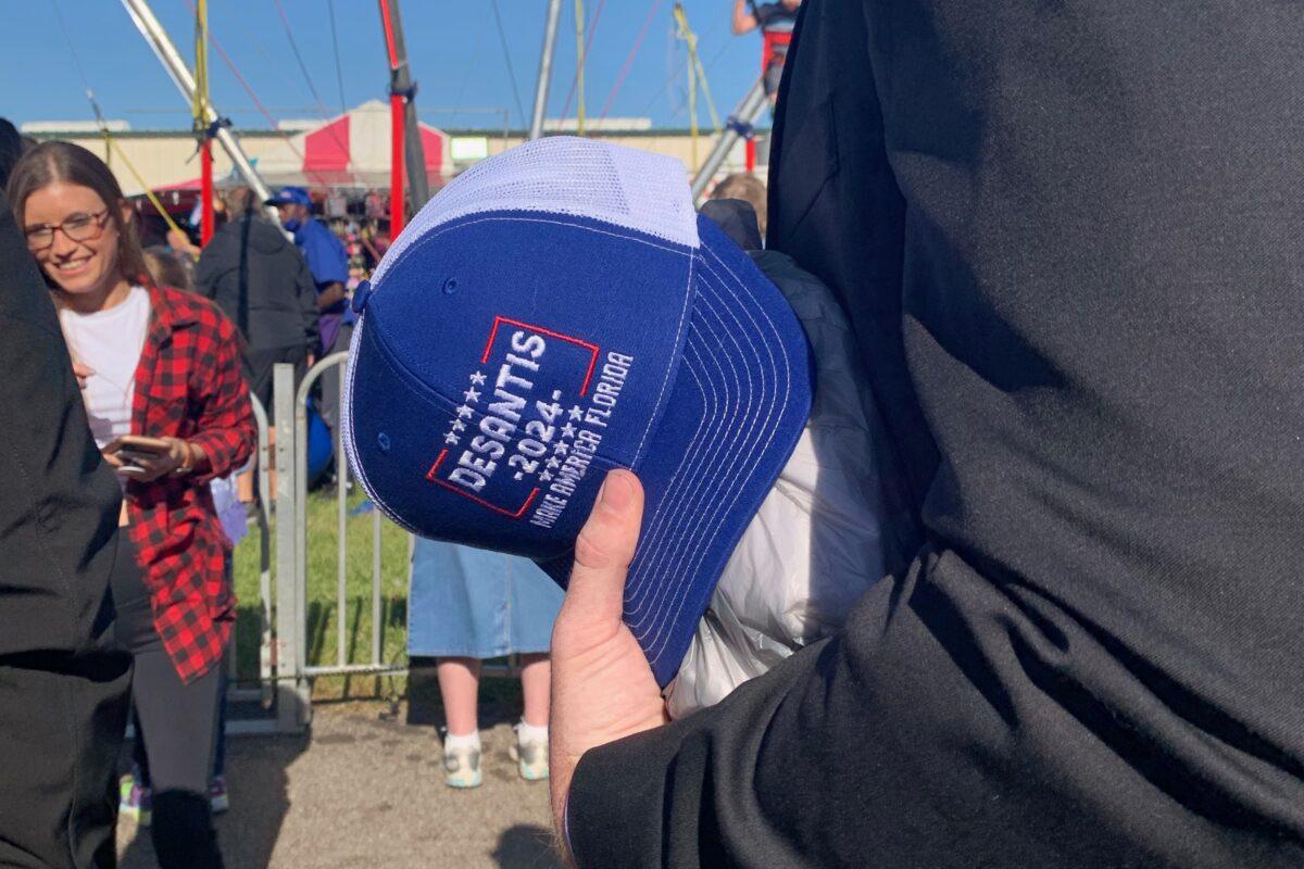 A staff member for Gov. Ron DeSantis holds a "DeSantis 2024, Make America Florida" hat at the Clay County fair on April 1, 2021. The staff member said the hat was handed to the governor by a fair attendee. (Ivan Pentchoukov/Epoch Times)