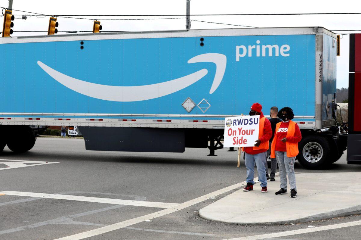 People hold a banner at the Amazon facility as members of a congressional delegation arrive to show their support for workers who will vote on whether to unionize, in Bessemer, Ala., on March 5, 2021. (Dustin Chambers/Reuters)