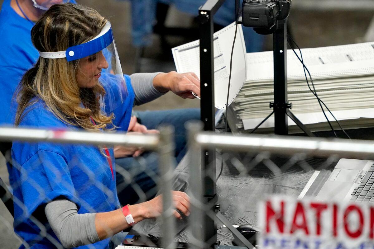 Workers examine ballots cast in Maricopa County in the 2020 election during an audit at Veterans Memorial Coliseum in Phoenix, Ariz., on May 6, 2021. (Matt York/AP Photo)