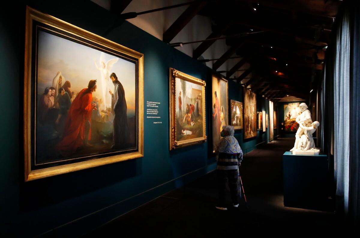 A woman looks at paintings at the “Dante. La visione dell’arte” (Dante. The Vision of Art) exhibition, in Forli, Italy, on May 8, 2021. (Antonio Calanni/AP Photo)