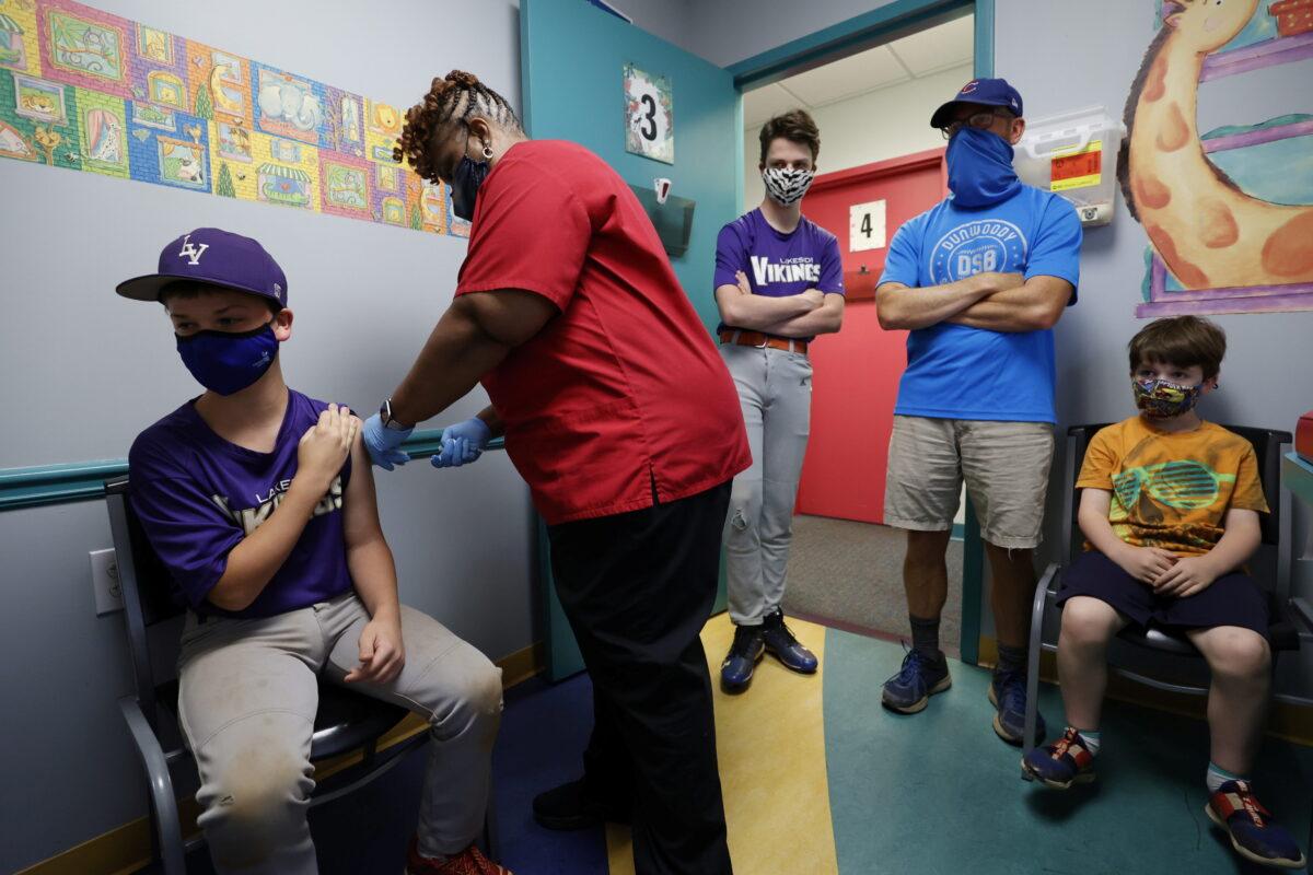 Family members watch as a 12-year-old is inoculated with Pfizer's vaccine against COVID-19 at Dekalb Pediatric Center in Decatur, Ga., on May 11, 2021. (Chris Aluka Berry/Reuters)