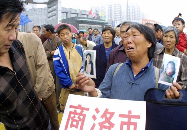 A peasant woman cries as she holds photos of her son who she alleged was brutalized and killed by local officials, as she joins other petitioners queueing outside a complaints bureau in Xian, central China's Shaanxi Province Aug. 18, 2005.  (STR/AFP via Getty Images)