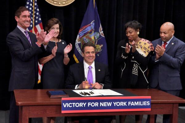 New York Gov. Andrew Cuomo, center, is applauded by New York Assembly Speaker, right, and New York Senate Majority Leader Andrea Stewart-Cousins, second from right, after he signed a law in New York on April 4, 2016. (Richard Drew/Pool/Getty Images)