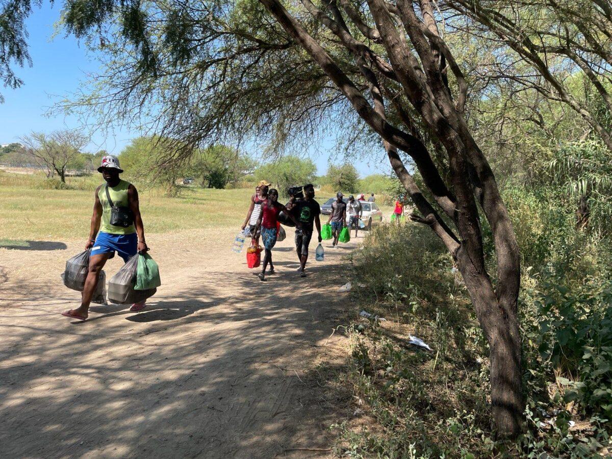 People carry supplies from Acuña, Mexico, on their way back to Del Rio, Texas, on Sept. 20, 2021. (Charlotte Cuthbertson/The Epoch Times)