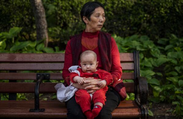 A woman holds a baby at a park in Beijing on May 12, 2021. (Kevin Frayer/Getty Images)