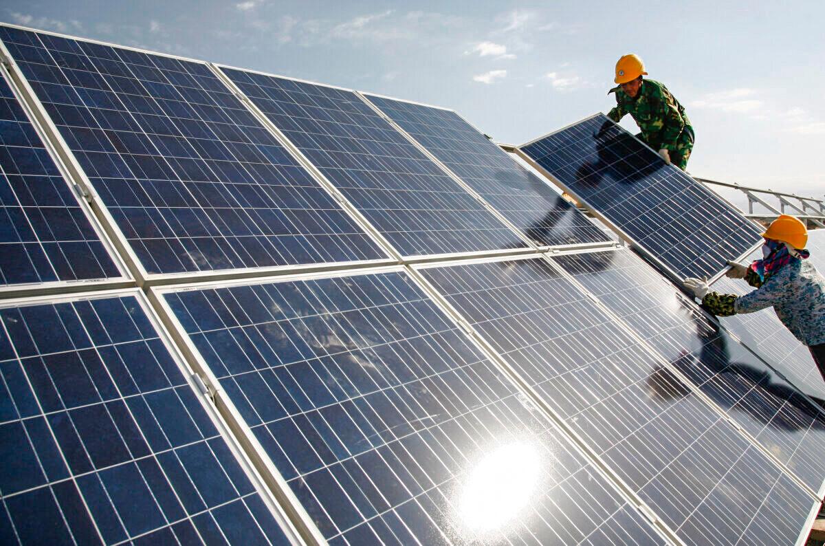 Workers install solar panels at a photovoltaic power station in Hami, Xinjiang Uyghur Autonomous Region, China, on Aug. 22, 2011. (Chinatopix via AP)