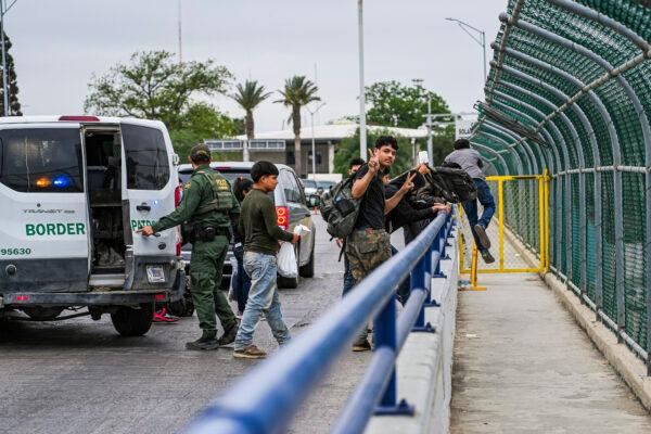 A Border Patrol agent drops a group of illegal immigrants being expelled under Title 42 at the halfway point of the international bridge between the United States and Mexico, in Eagle Pass, Texas, on April 19, 2022. (Charlotte Cuthbertson/The Epoch Times)