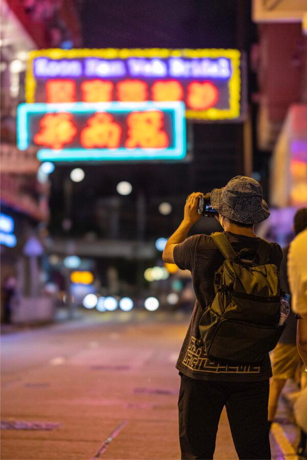 On the last light of the display of the neon signs of the long-established shop "Koon Nam Wah" in Yau Ma Tei, people came to take pictures. Aug. 16, 2022. (TM Chan/The Epoch Times)
