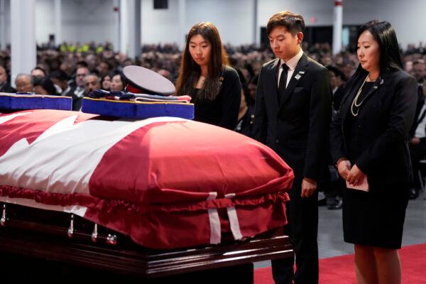 Jenny Hong, wife of Toronto Police Const. Andrew Hong, and her children Mia and Alex bow at his casket during his funeral service in Toronto on Sept. 21, 2022. (The Canadian Press/Frank Gunn)