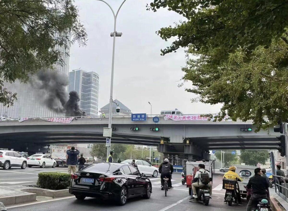 People take pictures of banners of political protest from an overpass in Beijing on Oct. 13, 2022. (Screenshot of Fangshimin’s Twitter account via The Epoch Times)