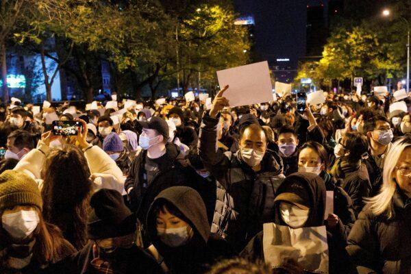 People hold white sheets of paper in protest of COVID-19 restrictions, after a vigil for the victims of a fire in Urumqi, in Beijing on Nov. 27, 2022. (Thomas Peter/Reuters)