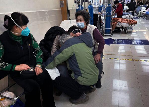 A man hugs an elderly relative as he and others offer support as she is cared for in the hallway of a busy emergency room at a hospital in Shanghai on Jan. 14, 2023. (Kevin Frayer/Getty Images)