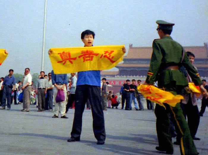 A Chinese policeman approaches a Falun Gong practitioner holding a banner with the Chinese characters for "truthfulness, compassion, and tolerance," the core tenets of Falun Gong, in Tiananmen Square, Beijing. (Courtesy of Minghui.org)