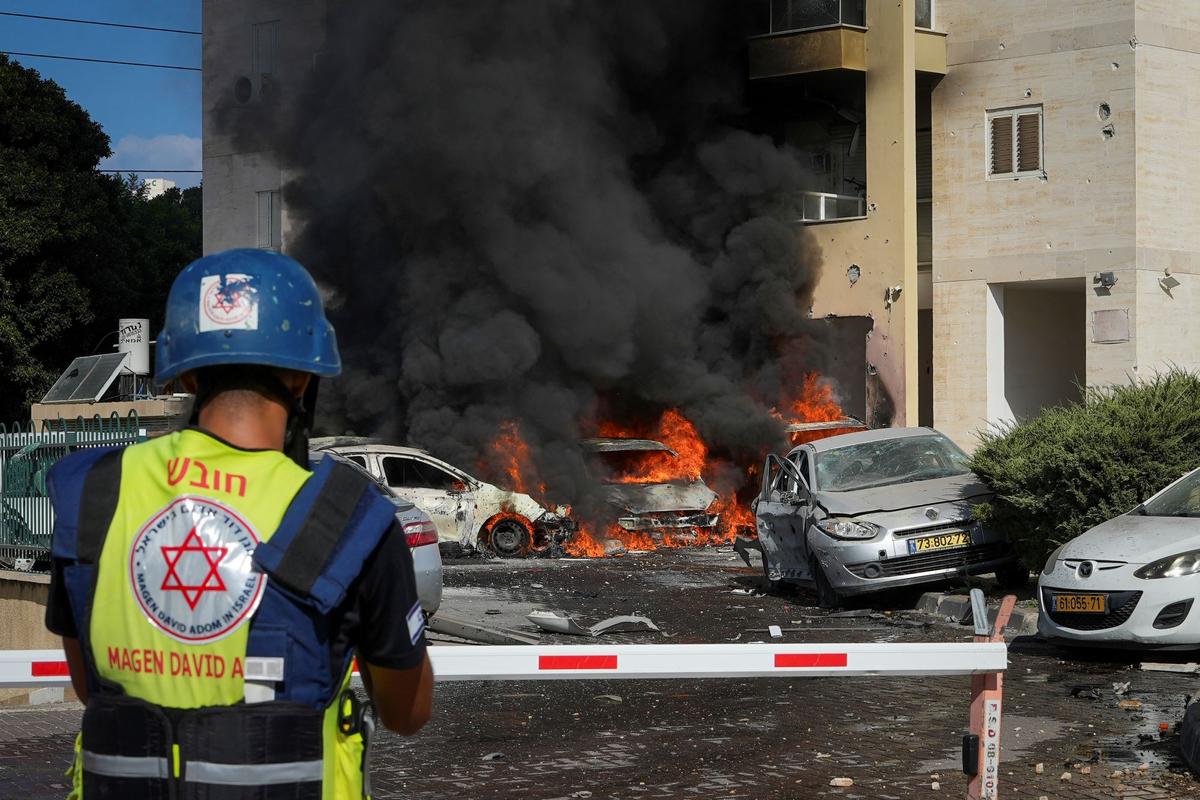 Cars burn after a rocket fired from the Gaza Strip hit a parking lot and a residential building in Ashkelon, Israel, on Oct. 7, 2023. (Tsafrir Abayov/AP Photo)