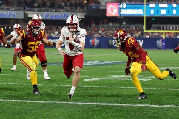 Evan Conley (6) of the Louisville Cardinals rushes for a touchdown past the defense of Elijah Hughes #56 and Jacobe Covington (14) of the USC Trojans during the first half of the DIRECTV Holiday Bowl against the USC Trojans in San Diego on Dec. 27, 2023. (Sean M. Haffey/Getty Images)