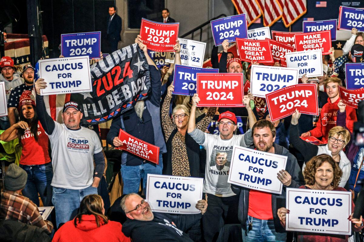 Supporters hold signs in front of TV cameras as they wait for the arrival of Republican presidential candidate Donald Trump speaks during a “Commit to Caucus” rally in Clinton, Iowa, on Jan. 6, 2024. (Tannen Maury/AFP via Getty Images)
