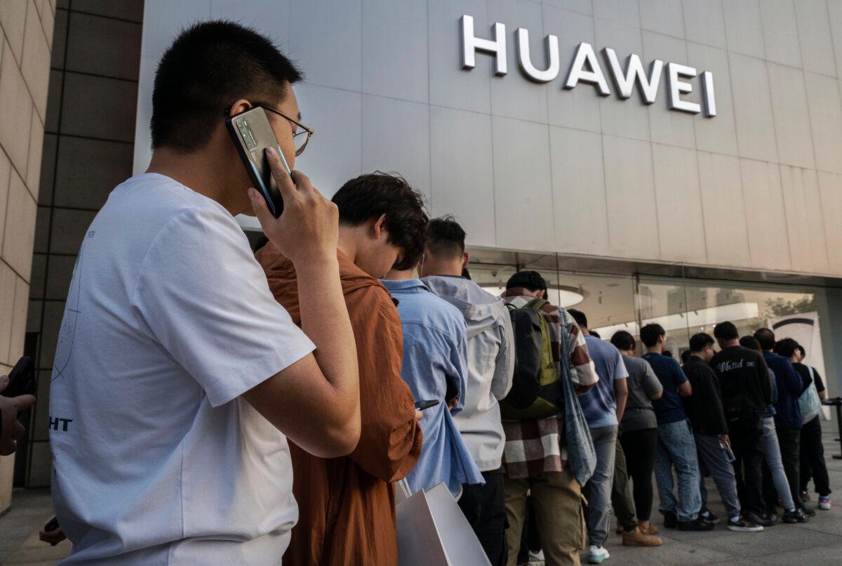A man talks on a Huawei mobile phone as he and others line up to buy or reserve a new Mate 60 smartphone and other products outside a Huawei flagship store after the company unveiled new products on September 25, 2023 in Beijing, China. (Kevin Frayer/Getty Images)