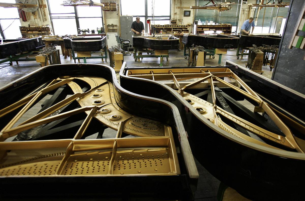 Technicians at the Steinway & Sons factory in Long Island City, New York, place soundboards into grand pianos. (Timothy A. Clary/Getty Images)
