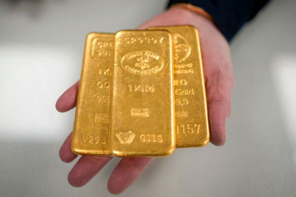 A jewelry quarter-gold dealer poses with three 1kg gold bullion bars in Birmingham, England, on Dec. 13, 2023. (Christopher Furlong/Getty Images)