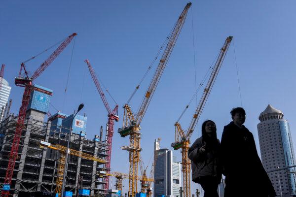 A young couple walk by a construction site near office buildings in the Central Business District in Beijing on March 2, 2024.(AP Photo/Andy Wong)
