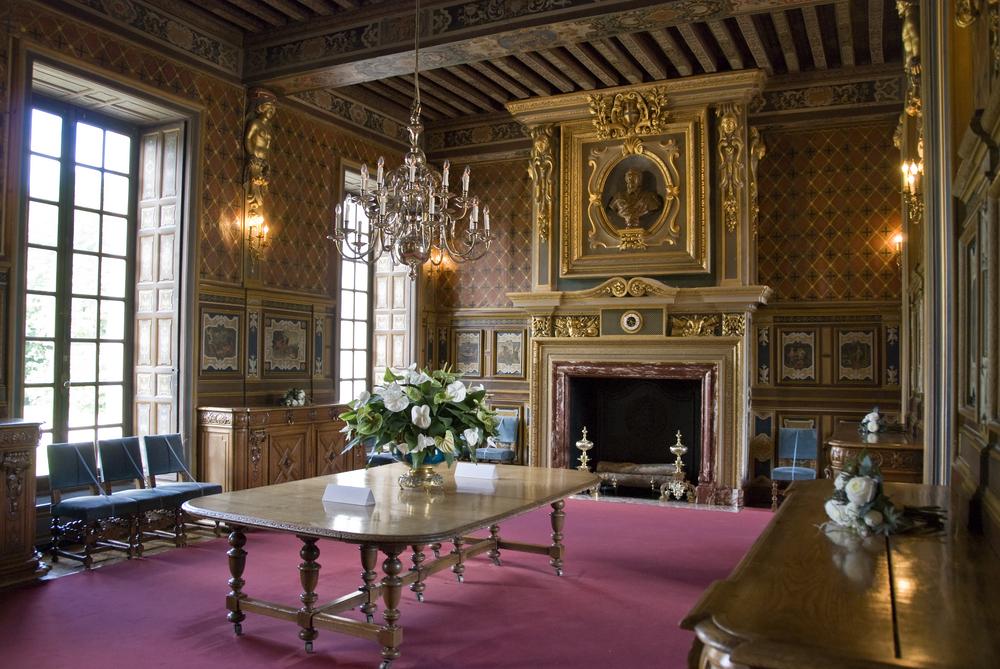 The dining room of Cheverny is characterized by its grand proportions and elegant décor. The room’s high ceilings are adorned with wooden beams, while tall windows flood the space with natural light. A large wooden table serves as the focal point for the room, while the grand fireplace adds to the ambiance, its mantel adorned with gilded framing. (DOPhoto/Shutterstock)