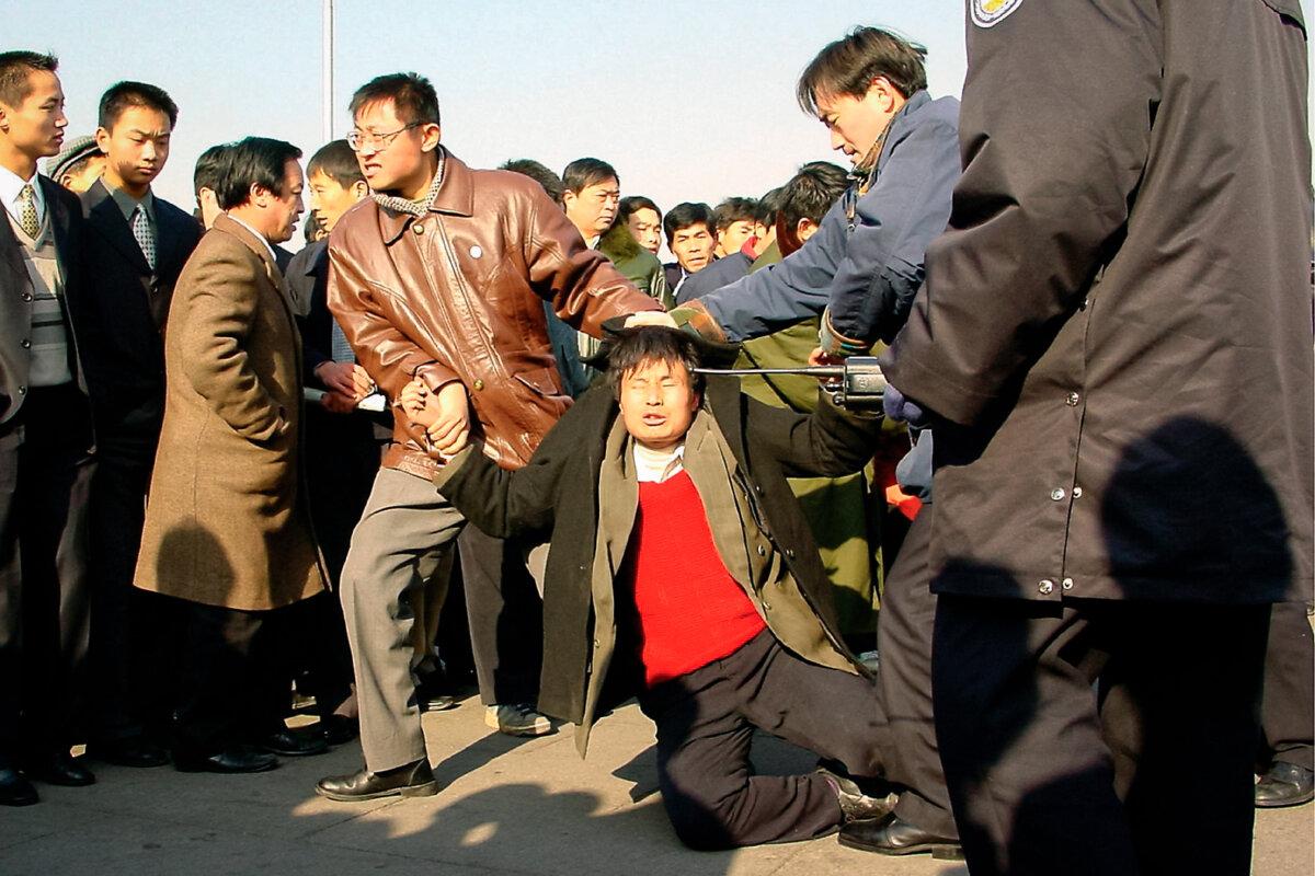 Two plainclothes police officers arrest a Falun Gong practitioner at Tiananmen Square in Beijing on Dec. 31, 2000. (Minghui)