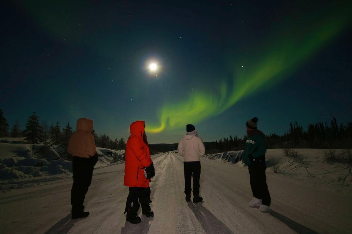 Tour participants witness an aurora with a waning gibbous moon near Yellowknife in December 2024. (Courtesy of Joe Buffalo Child)