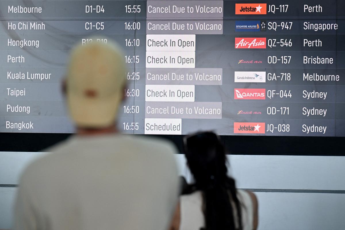 Passengers look at an electronic board displaying cancelled flights after the nearby Mount Lewotobi Laki-Laki volcano erupted, at Ngurah Rai International Airport in Tuban near Denpasar, on Indonesia's resort island of Bali on June 18, 2025. (Sonny Bumbelaka/AFP via Getty Images)