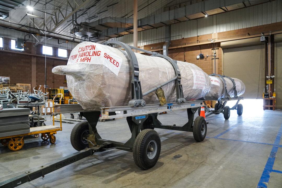 (Top) An F-16 jet fighter is dismantled for parts at Davis-Monthan Air Force Base in Tucson, Ariz., on April 21, 2026. (Bottom Left) Reusable fuel tanks from an F-16C jet fighter at Davis-Monthan Air Force Base in Tucson, Ariz., on April 21, 2026. (Bottom Right) An F-16 jet engine ready for delivery at the 309th Aerospace Maintenance and Regeneration Group in Tucson, Ariz., on April 21, 2026. (Allan Stein/The Epoch Times)