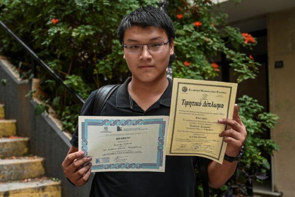 Jiang Semniao, 18, a Golden Visa holder, poses holding up his awards and diplomas in central Athens on Oct. 31, 2019. (ARIS MESSINIS/AFP via Getty Images)