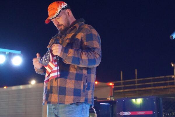 Brian Brase, co-organizer of The People's Convoy, holds a flag gifted to him by a WWII veteran, while speaking to a rally in Hagerstown, Md., on March 4, 2022. (Enrico Trigoso/The Epoch Times)