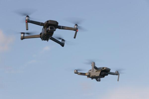 A DJI Mavic 2 Pro and DJI Mavic Mini made by the Chinese drone maker DJI Technology Co. Ltd. fly near each other in Miami on Dec. 15, 2021. (Joe Raedle/Getty Images)
