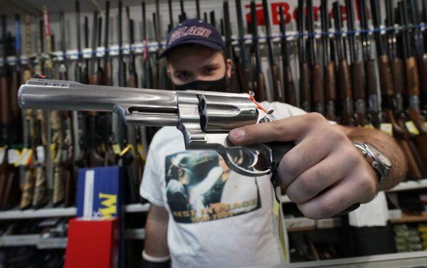 A salesman shows off weapons for sale at Coliseum Gun Traders in Uniondale, N.Y., on Sept. 25, 2020. (Timothy A. Clary/AFP via Getty Images)