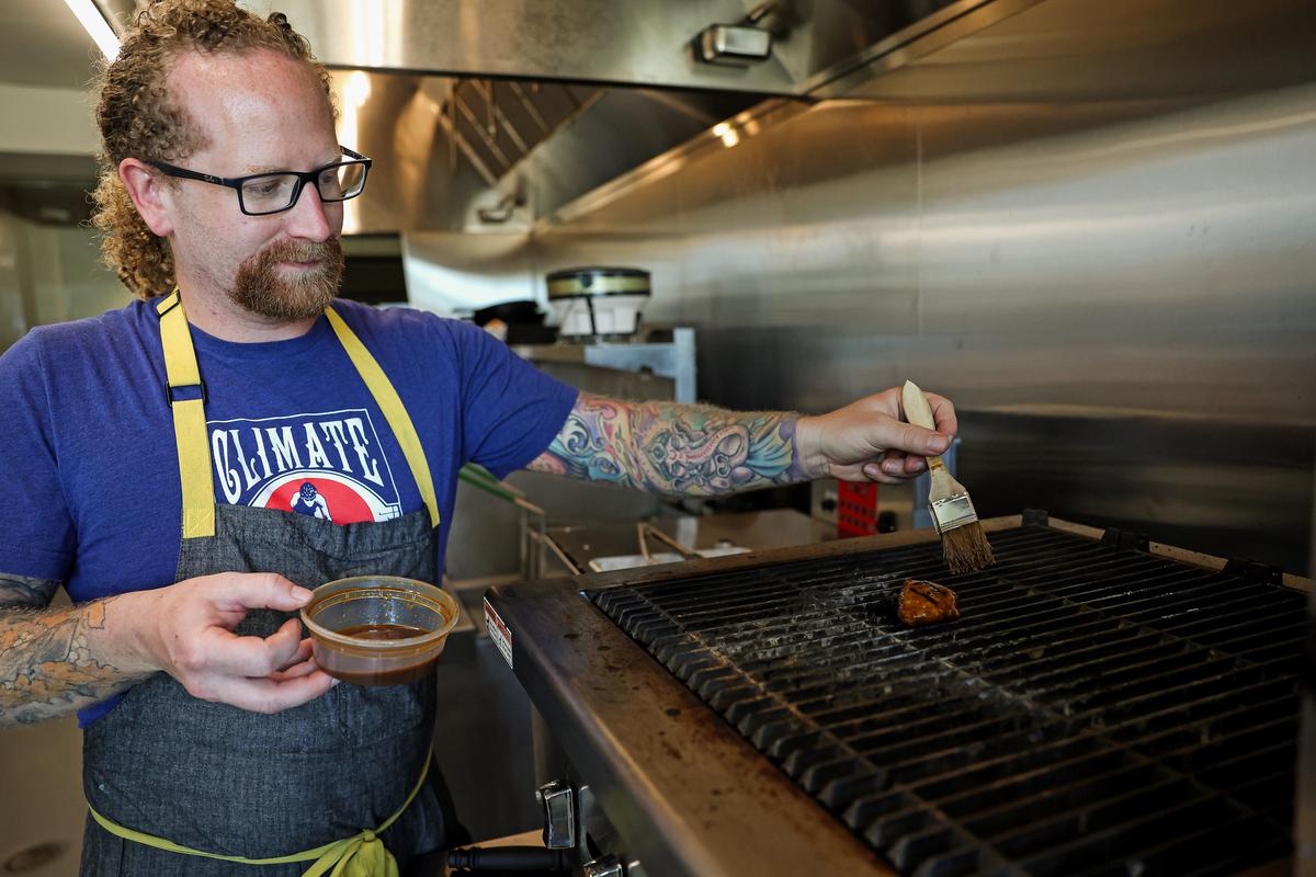 Chef Zach Tyndall brushes sauce on a piece of Good Meat's cultivated chicken as it's grilled at the Eat Just office in Alameda, Calif., on July 27, 2023. In June, the U.S. Department of Agriculture authorized two California-based companies, Upside Foods and Good Meat, to sell chicken grown from cells in a lab. (Justin Sullivan/Getty Images)