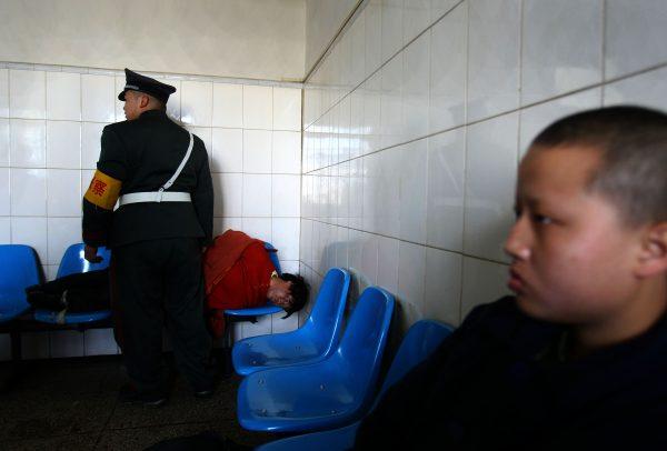 A man who was just escorted to the Kunming Mental Hospital lies on chairs in Kunming, Yunnan Province, southwest China, on Dec. 1, 2007. (China Photos/Getty Images)