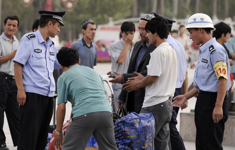 Police check identity cards of ethnic Uyghurs and search their bags in Xinjiang in China's far northwestern, mainly Muslim region. (Peter Parks/AFP/Getty Images)