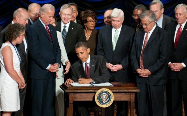 President Barack Obama signs the Dodd-Frank Wall Street Reform and Consumer Protection Act alongside members of Congress, the administration and Vice President Joe Biden at the Ronald Reagan Building in Washington on July 21, 2010. (Photo ROD LAMKEY JR/AFP/Getty Images)