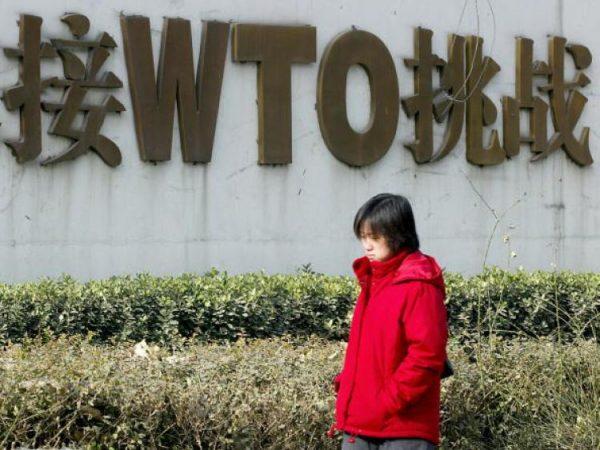 A Chinese woman walks past a billboard boasting China's World Trade Organization (WTO) membership. (Goh Chai Hin/AFP/Getty Images)