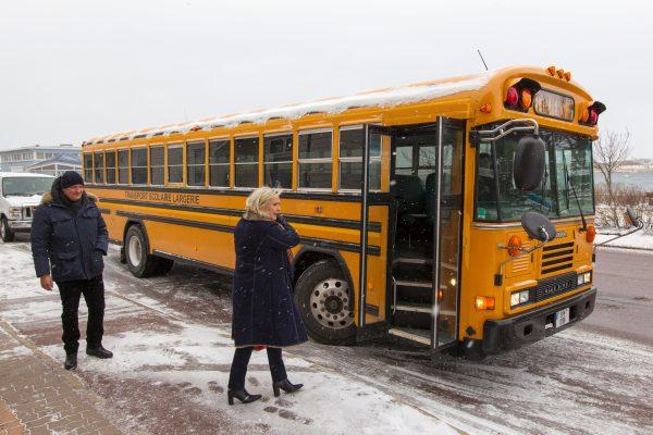 Marine Le Pen and her bodyguard Thierry Legier board a school bus for a guided tour during a two-day visit to the French-controlled islands of Saint Pierre and Miquelon, off the coast of Canada, on March 23, 2016. (Chantal Briand/AFP/Getty Images)