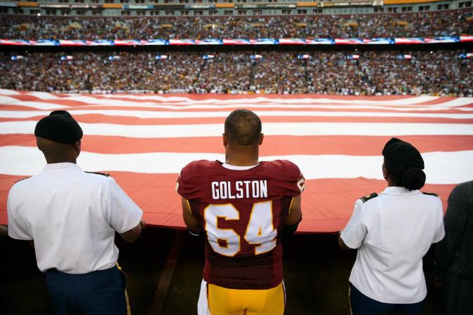 Redskins Players Join Armed Forces Members in Holding Flag During National Anthem