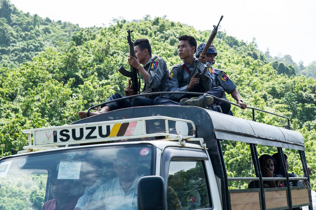 Burmese police sit on the roof of a truck as they provide protection for staff from the United Nations (UN) and International Non-Governmental Organizations (INGOs) after a visit to a conflict area, at a check point near the entrance of Maungdaw township in Myanmar's Rakhine State on Aug. 28, 2017.<br/>(STR/AFP/Getty Images)