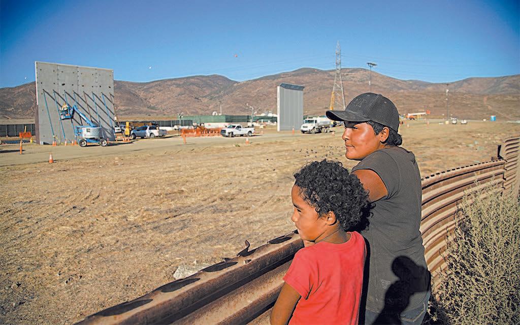 A mother and daughter watch the construction of border wall prototypes in San Diego, from Tijuana, Mexico, on Oct. 5. (SANDY HUFFAKER/GETTY IMAGES)