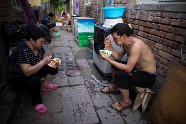 People eat dinner on the streets of a migrant village on the outskirts of Beijing, on Aug. 17, 2017. (Nicolas Asfouri/AFP/Getty Images)