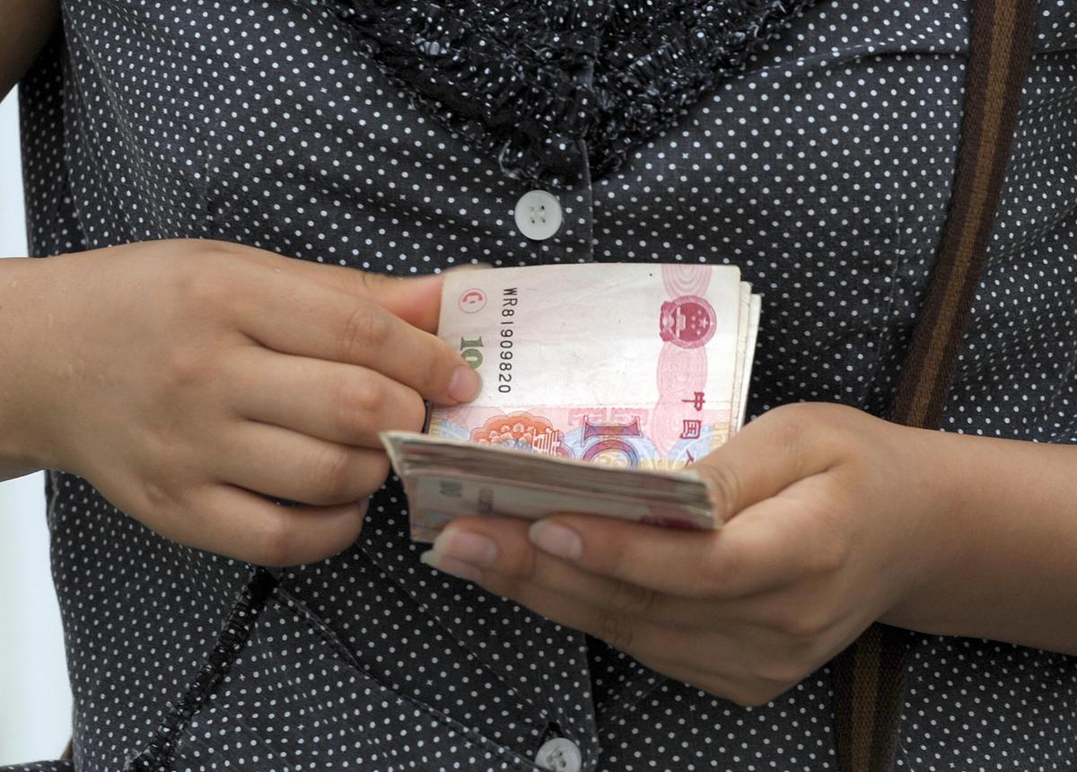 A woman counting Chinese banknotes along a street in Beijing on September 11, 2009. (Liu Jin/AFP/Getty Images)