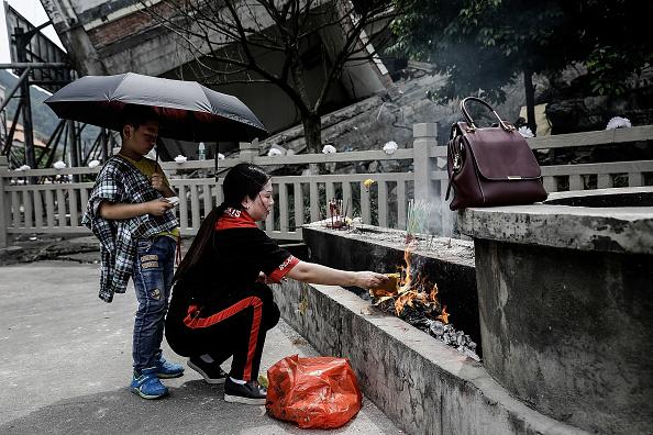 Relatives of earthquake victims burn offerings at the ruins of earthquake-hit Beichuan county during the ten year anniversary of the Earthquake on May 12, 2018 in Beichuan Qiang Autonomous County, Sichuan province China. (Wang He/Getty Images)