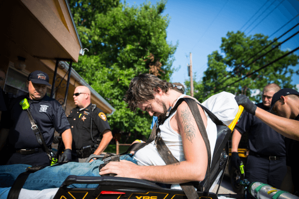 Local law enforcement and emergency services assist a man who is overdosing in the Drexel neighborhood of Dayton, Ohio, on Aug. 3, 2017. (Benjamin Chasteen/The Epoch Times)